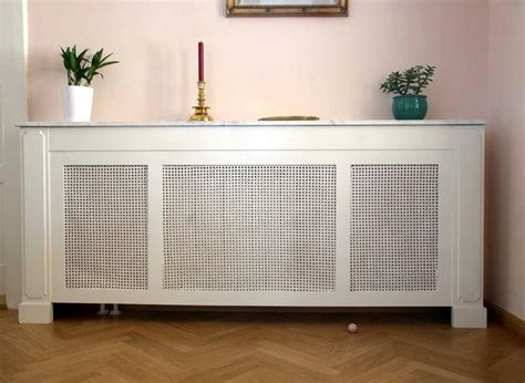 A White Cabinet With Two Plants On Top And A Painting Above It In A