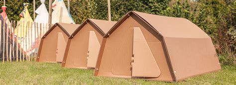 Three Cardboard Houses Sitting In The Grass Next To Each Other On Top