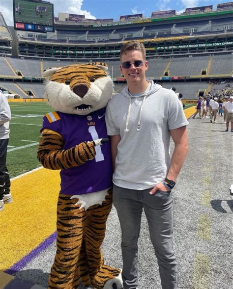 A Man Standing Next To A Tiger Mascot On Top Of A Field At A Football Game