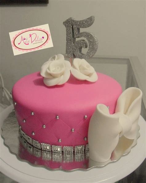 A Pink Cake With White Flowers And Silver Decorations