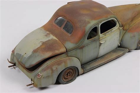 An Old Rusted Out Toy Car Sitting On Top Of A White Surface