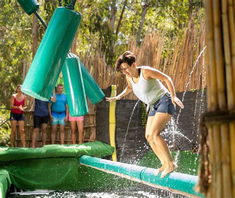 Happy Brunette Crossing Pool Of Water On Inflatable Log With Hanging