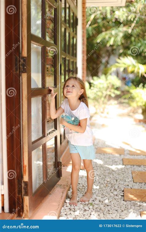 Little American Girl Standing Near Door With Toy Outside Palms In