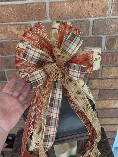 a hand is holding a large bow on top of a mailbox in front of a brick wall