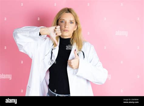 Junge blonde Ärztin Stethoskop trägt und über einem isolierten rosa Hintergrund steht und