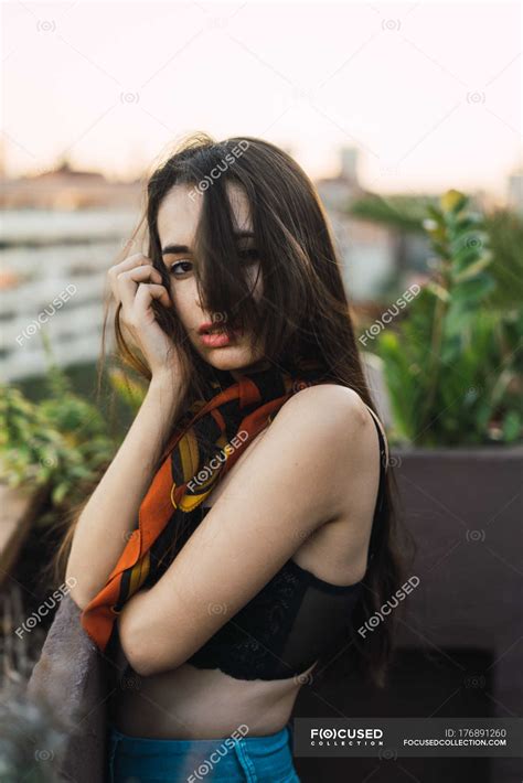 Portrait Of Brunette Girl Posing On Balcony And Looking At Camera Cityscape Woman Stock