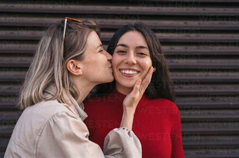 Girl Friends Kissing On The Cheek Blonde And Brunette Stock Photo