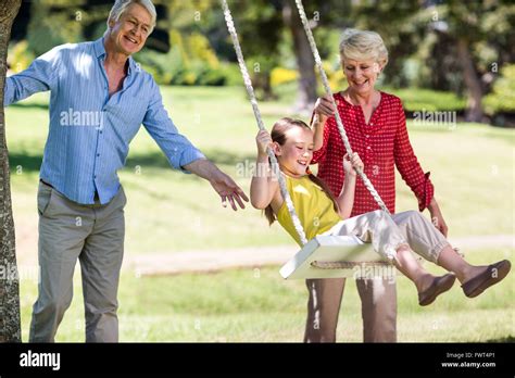grandparents pushing  granddaughter  swing stock photo alamy