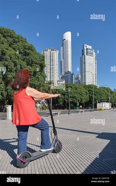 Latin Mature Woman Riding Her Electric Kick Scooter Around The City In Summer Concepts Of