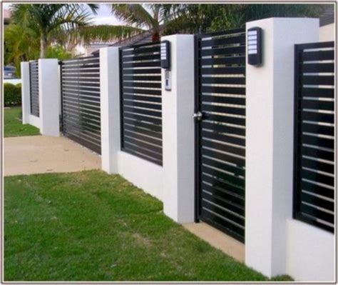 A Row Of Black And White Fenced In Area With Grass On The Side Walk