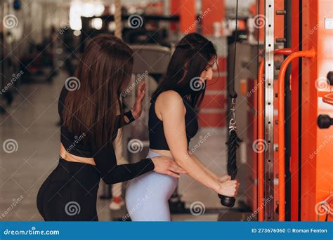 Female Personal Trainer Corrects And Advises Her Brunette Client During Training In The Gym