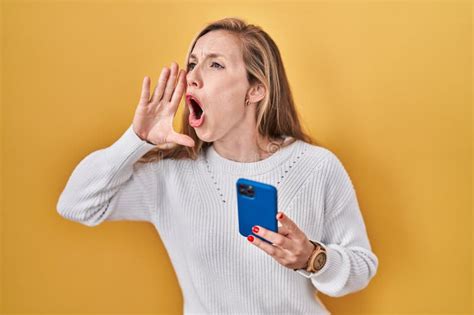 Jeune Femme Blonde Utilisant Un Smartphone Taper Un Message Criant Et Hurlant Haut En Bas Avec