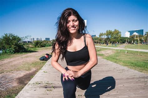 Mulher latina caucasiana desportiva esticando as pernas olhando para a câmera e sorrindo Foto