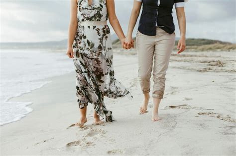 Premium Photo Low Section Of Lesbian Couple Holding Hands While Walking At Beach