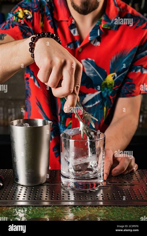 Bartender Putting A Crystal Clear Ice Cube Into A Rocks Glass Tiki