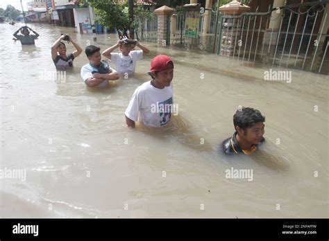 Surakarta, Indonesia. 17th Feb, 2023. People wade through flood water ...