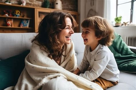 Feliz madre latina joven y hijo pequeño divirtiéndose en el sofá acogedor en la sala de estar