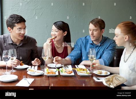 Four friends eating food in restaurant Stock Photo - Alamy