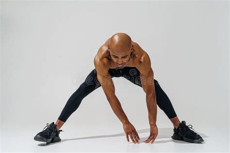 Athletic Man With Naked Torso Doing Body Stretching Exercises Before Workout On Studio