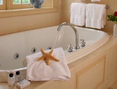 A Starfish Sits On The Edge Of A Bathtub Next To Two White Towels