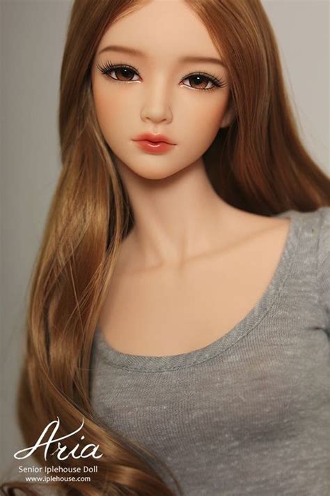 A Doll With Long Blonde Hair Wearing A Gray Shirt And Silver Necklace On It S Neck
