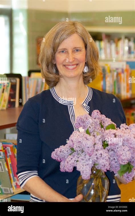 Happy First Grade Teacher Holding A Bouquet Of Purple Lilacs In Her