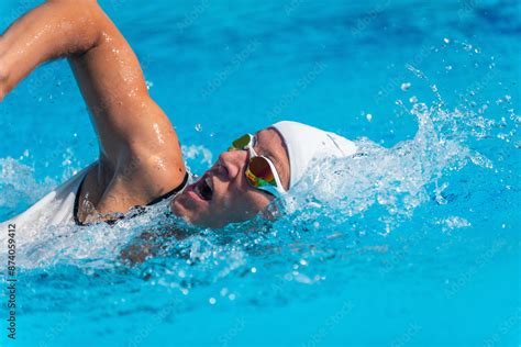 Female Swimmer In White Swim Cap And Goggles Performing Freestyle