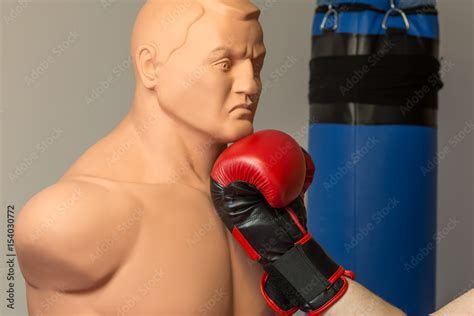 Red Boxing Gloves Punching An Uppercut On The Chin Of A Dummy Mannequin Doll On A Gym With A