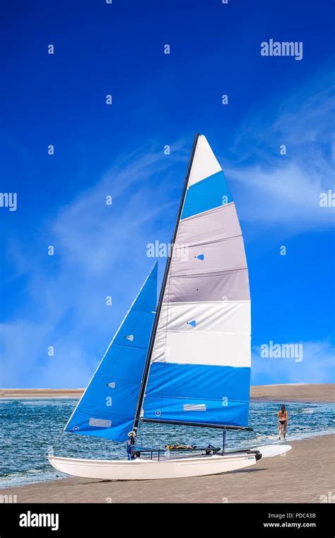 Ein blau weißes Segelboot am Strand mit Mädchen im Bikini zu Fuß Stockfotografie Alamy