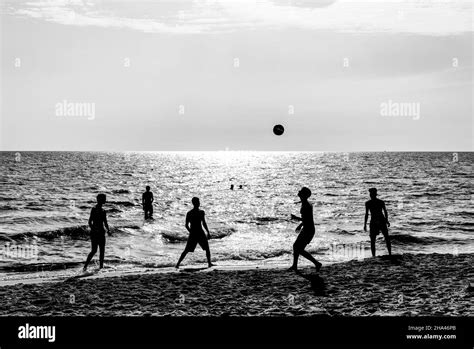 Happy friends playing football on the beach at sunset - Silhouettes of ...