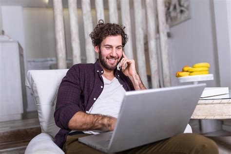 Chico sonriente atractivo joven está navegando en su computadora