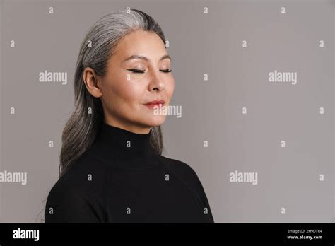 Mature Asian White Woman Posing With Her Eyes Closed Isolated Over Grey Background Stock Photo