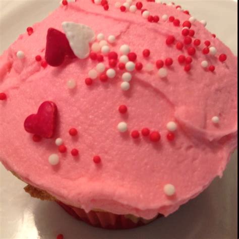 White Cupcakes With Pink Buttercream Icing And Valentine Sprinkles With Candy Heart Sprinkles