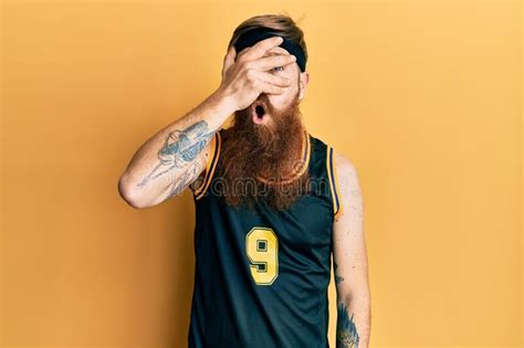 Redhead Man With Long Beard Wearing Basketball Uniform Peeking In Shock