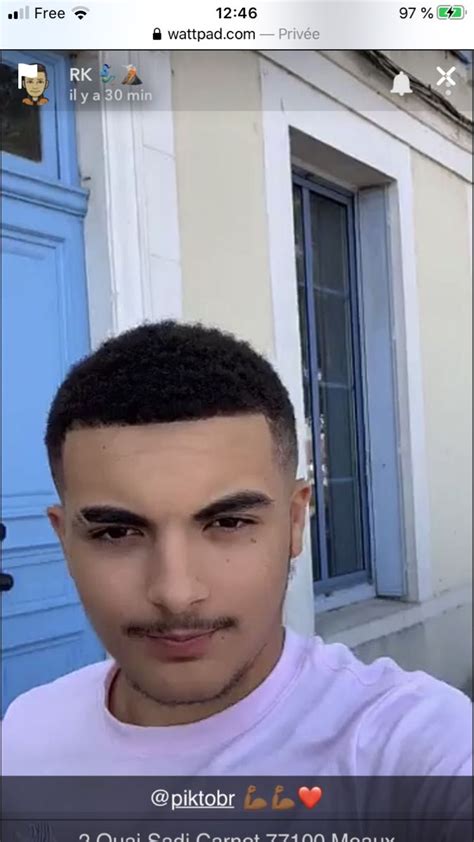 A Man Is Taking A Selfie In Front Of A Blue Door With His Hair Pulled Back