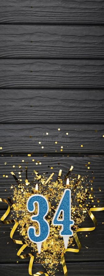 Number 34 Blue Celebration Candle And Gold Confetti On Dark Wooden