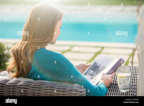 Brunette Woman Reading Magazine At Luxury Poolside Stock Photo Alamy