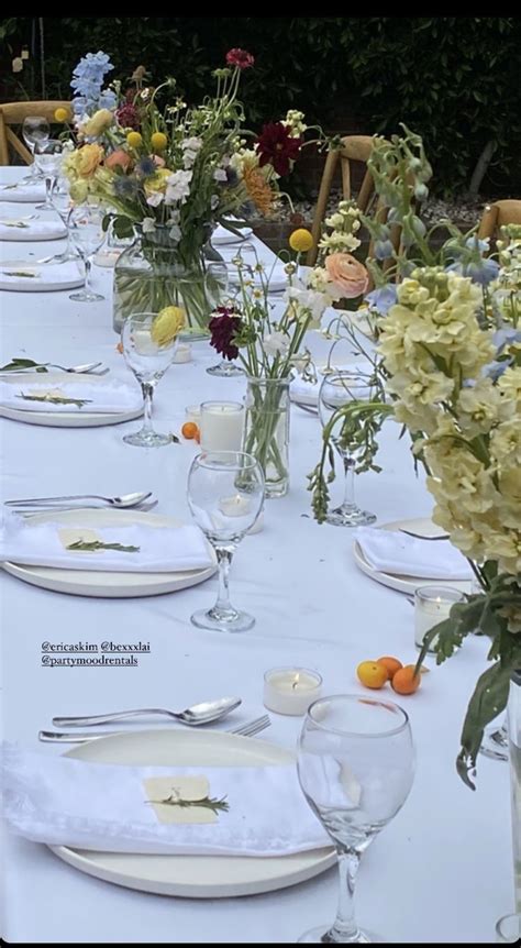 A Long Table Is Set With Flowers And Plates