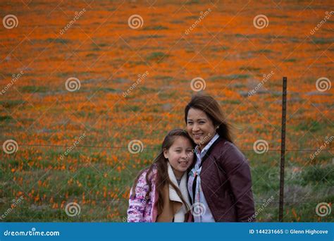 Latina Mother And Daughter In Front Of Desert California Poppy Field Orange Bokeh Stock Image