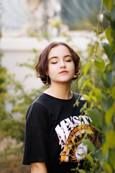 A Woman Leaning on a Concrete Railing with Her Head Up and Eyes Closed