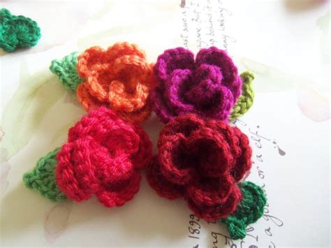 Four Crocheted Flowers Sitting On Top Of An Open Book