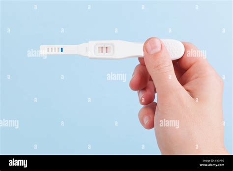 Male Hand Holding Positive Pregnancy Test Isolated On Light Blue