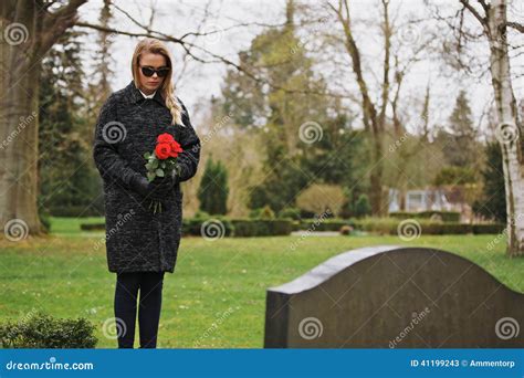 Mujer Que Se Aflige En El Cementerio Que Sostiene Las Flores Imagen De