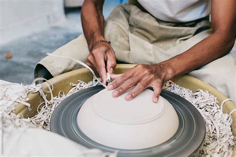 Closeup Of Artisan Potter S Hands Making Plate On Flywheel By Stocksy