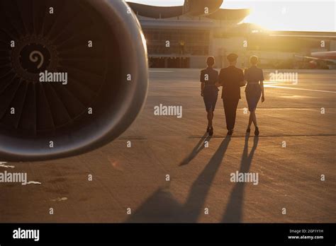 Full Length Shot Of Professional Pilot Walking Together With Two Female