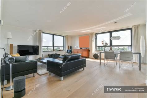 Comedor contemporáneo interior con mesa contra sofás y TV en casa con