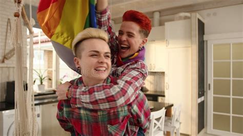 Playful Lesbian Couple Piggybacking And Waving LGBT Flag Indoors Stock Footage Video Of Unity