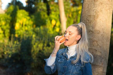 Jolie Jeune Femme Blonde Avec Une Queue De Cheval Dans Ses Cheveux Portant Une Robe Denim Tient