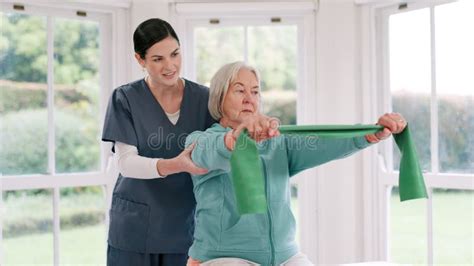 Woman Nurse And Senior Patient With Resistance Band In Physiotherapy