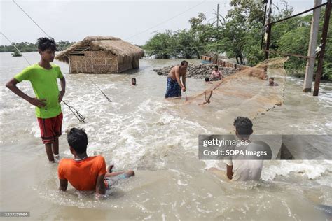 A Man Tries To Catch Fish From The Flood Water In The Coastal Village